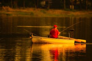 man in red cap and shirt fishing in lake