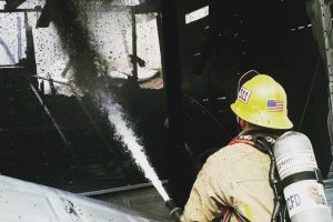 Firefighter using fire hose to battle blaze