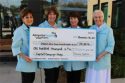 (From left) Volunteer leadership Sylvia Weinmeister, Vonnie Hobbs, Linda Monroe and Martha Cover pose with the check commemorating the volunteer force’s $100,000 pledge.