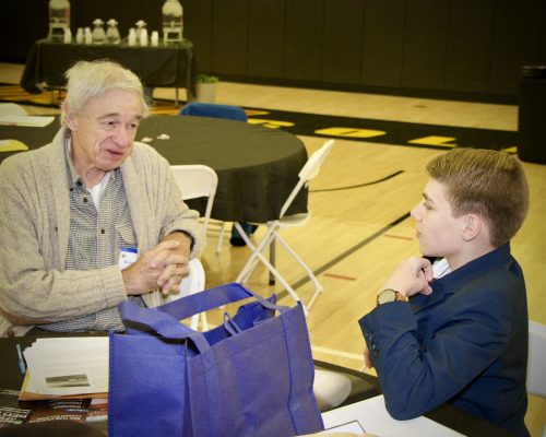 Older gentleman talking with young student