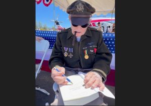 Lt. Dennis Thompson signs a book at the 2024 Father's Day Fly-In (photo by Traci Williams-O'Neil)
