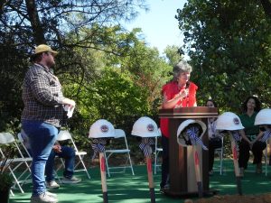 Clois Irwin speaks, with Joseph Mathiesen-Powell to the left