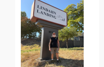 Roger Lindahn in front of Lindahn Landing sign - courtesy image