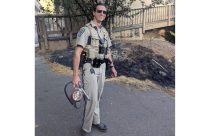 Officer Kannon Gibson with fire extinguisher and the burnt ground behind him where he put out the flames—CHP photo